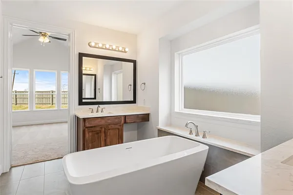 a bathroom with a tub a sink and a window