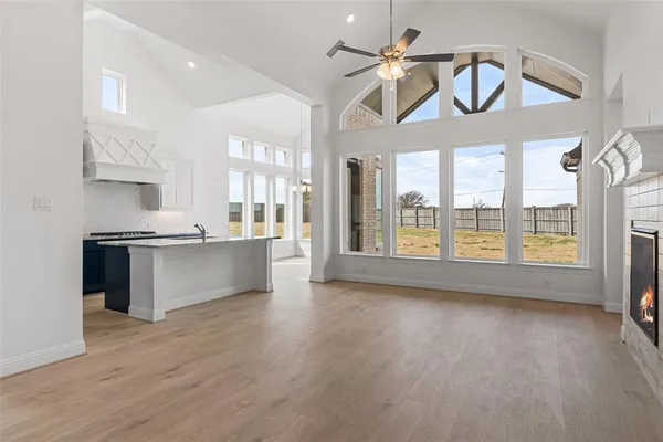 a view of large kitchen with granite countertop a stove a sink a refrigerator and a dining table with wooden floor