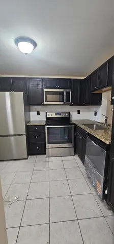 a kitchen with kitchen island granite countertop a stove a sink and a refrigerator