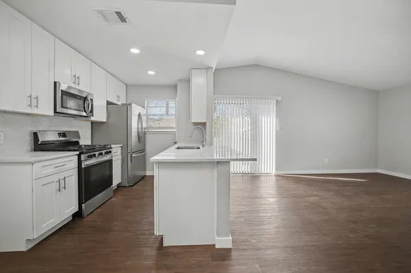 a large kitchen with stainless steel appliances granite countertop a stove a sink and a refrigerator