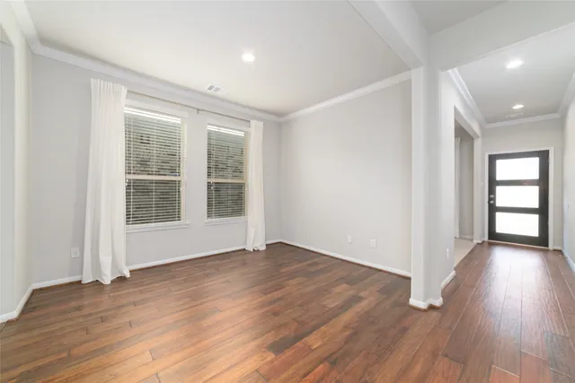 a view of an empty room with wooden floor and windows