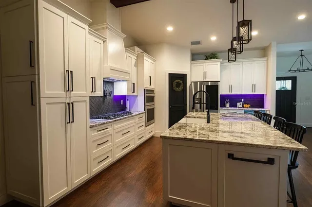 a kitchen with stainless steel appliances kitchen island granite countertop a sink and refrigerator