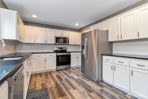 a kitchen with granite countertop white cabinets and stainless steel appliances