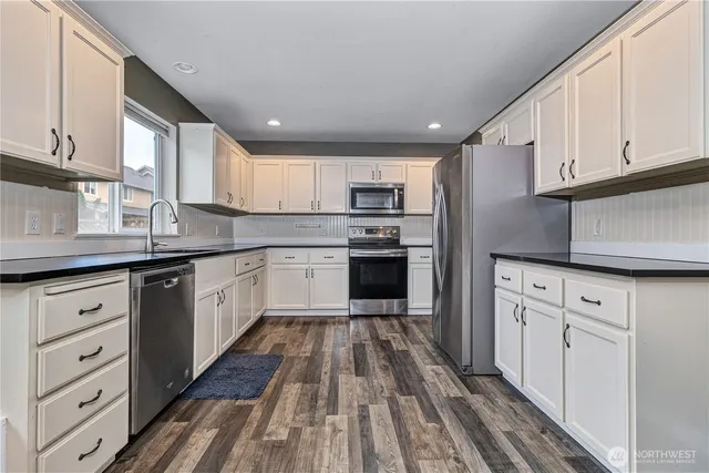 a kitchen with cabinets stainless steel appliances a sink and a window