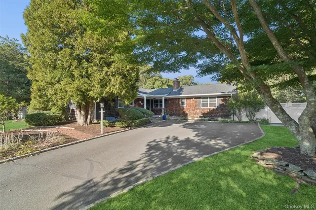 a front view of a house with a garden and trees