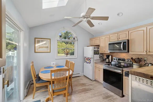 a kitchen with stainless steel appliances a stove a sink dishwasher a dining table and chairs with wooden floor