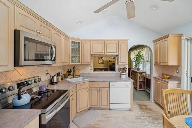 a kitchen with stainless steel appliances granite countertop a stove a sink dishwasher a refrigerator and a microwave oven with white cabinets