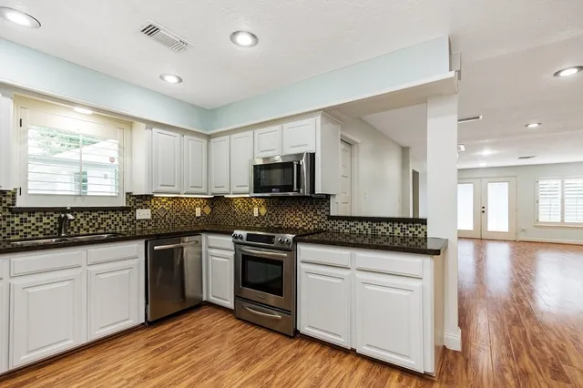 a kitchen with granite countertop a sink and steel appliances