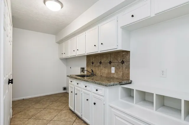 a kitchen with granite countertop white cabinets and stainless steel appliances