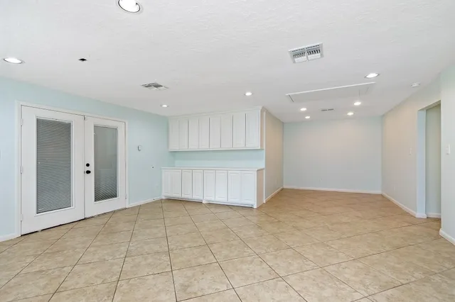 a view of an empty room with kitchen and chandelier