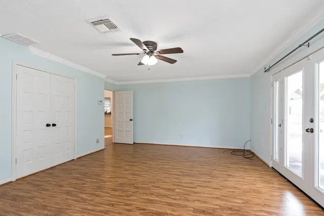a view of empty room with wooden floor and fan