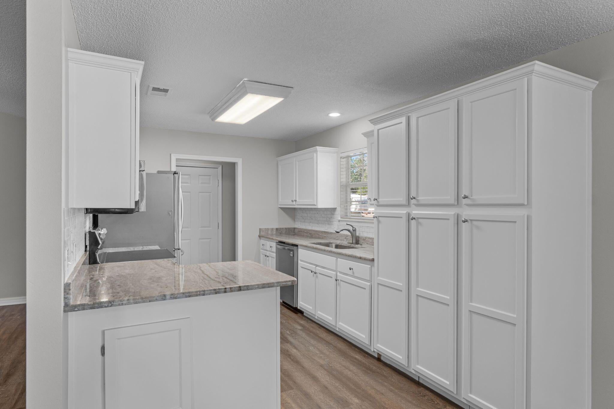 8134 Menorca Street Navarre, FL 32566 - Photo 12 of 54 a kitchen with granite countertop white cabinets and white appliances