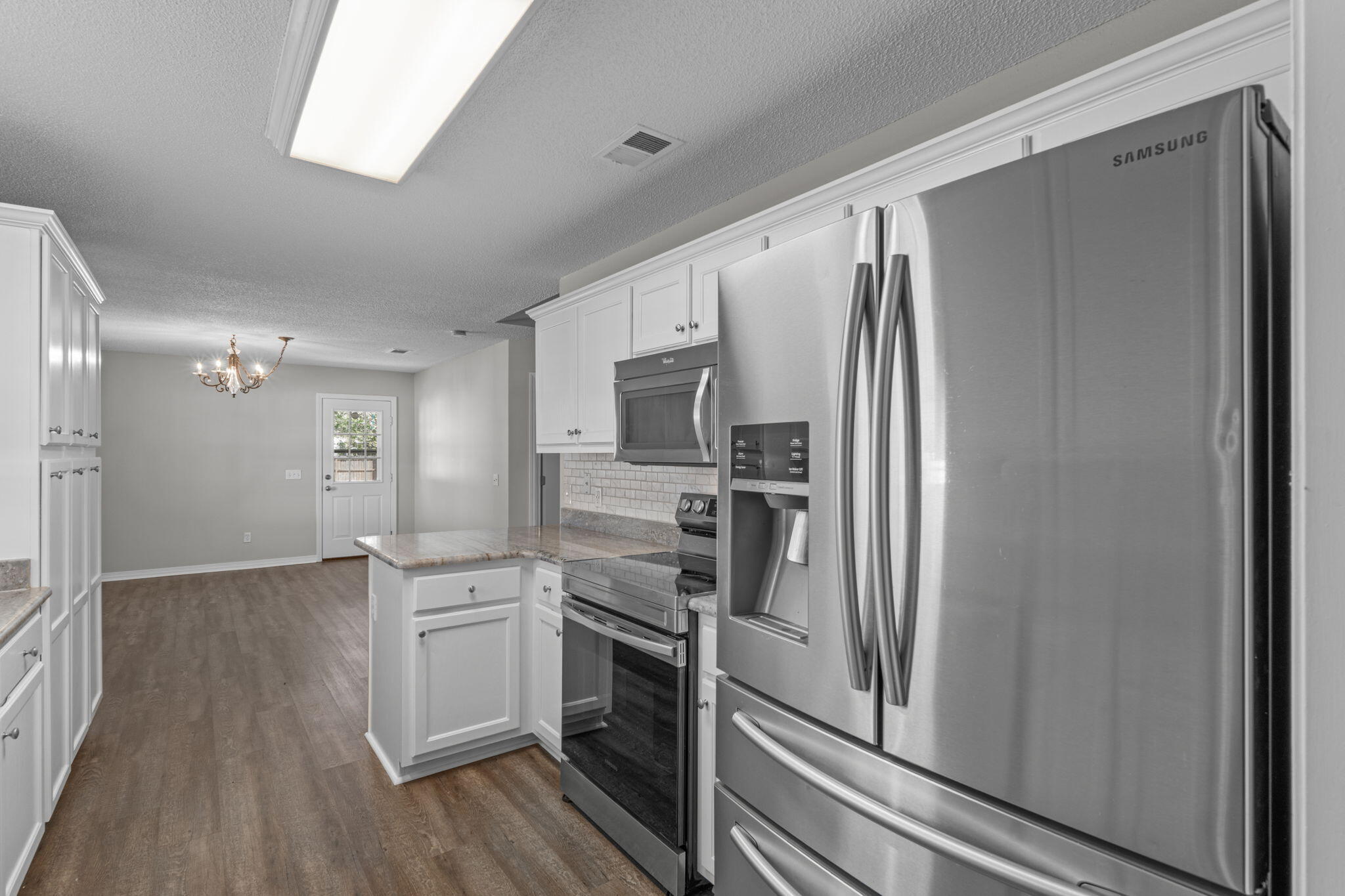 8134 Menorca Street Navarre, FL 32566 - Photo 14 of 54 a kitchen with a refrigerator stainless steel appliances wooden floor and cabinets
