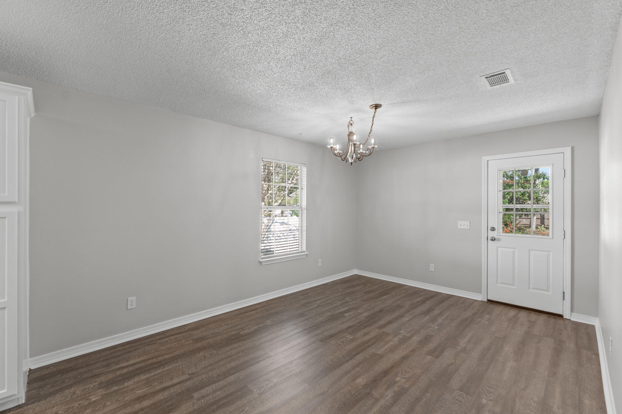 8134 Menorca Street Navarre, FL 32566 - Photo 10 of 54 an empty room with wooden floor chandelier and windows