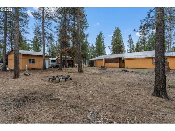 a backyard of a house with large trees and covered with wooden fence