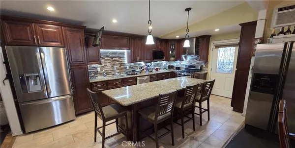 a kitchen with stainless steel appliances granite countertop a dining table chairs refrigerator refrigerator and microwave