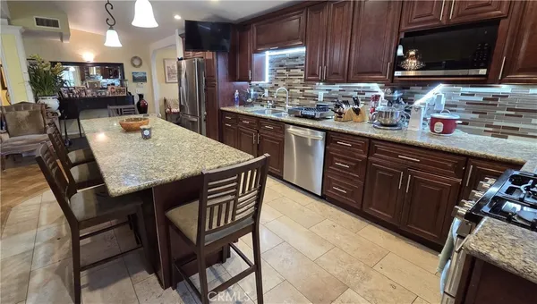 a kitchen with stainless steel appliances granite countertop a table chairs and a refrigerator