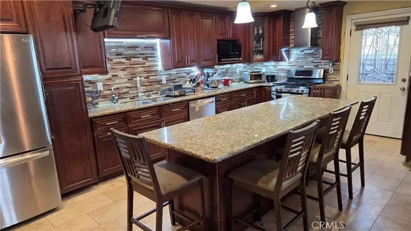 a kitchen with stainless steel appliances granite countertop table chairs sink and cabinets