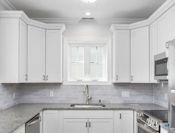 a kitchen with granite countertop white cabinets and white appliances