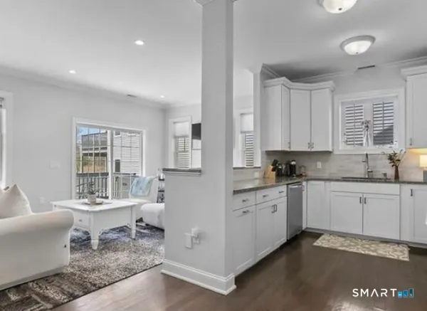 a large white kitchen with granite countertop lots of white cabinets a granite counter tops and a window