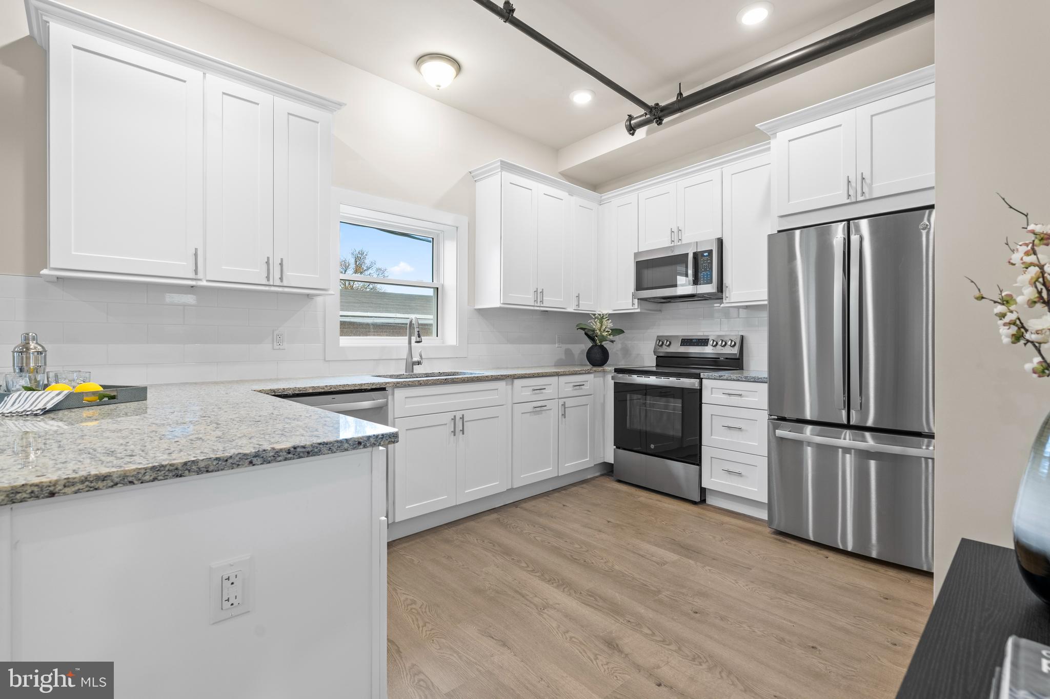 30 West Broad Street Souderton, PA 18964 - Photo 6 of 38 a kitchen with granite countertop a refrigerator oven a sink dishwasher and white cabinets with wooden floor