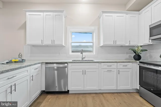 a kitchen with stainless steel appliances a refrigerator a stove a sink and chairs