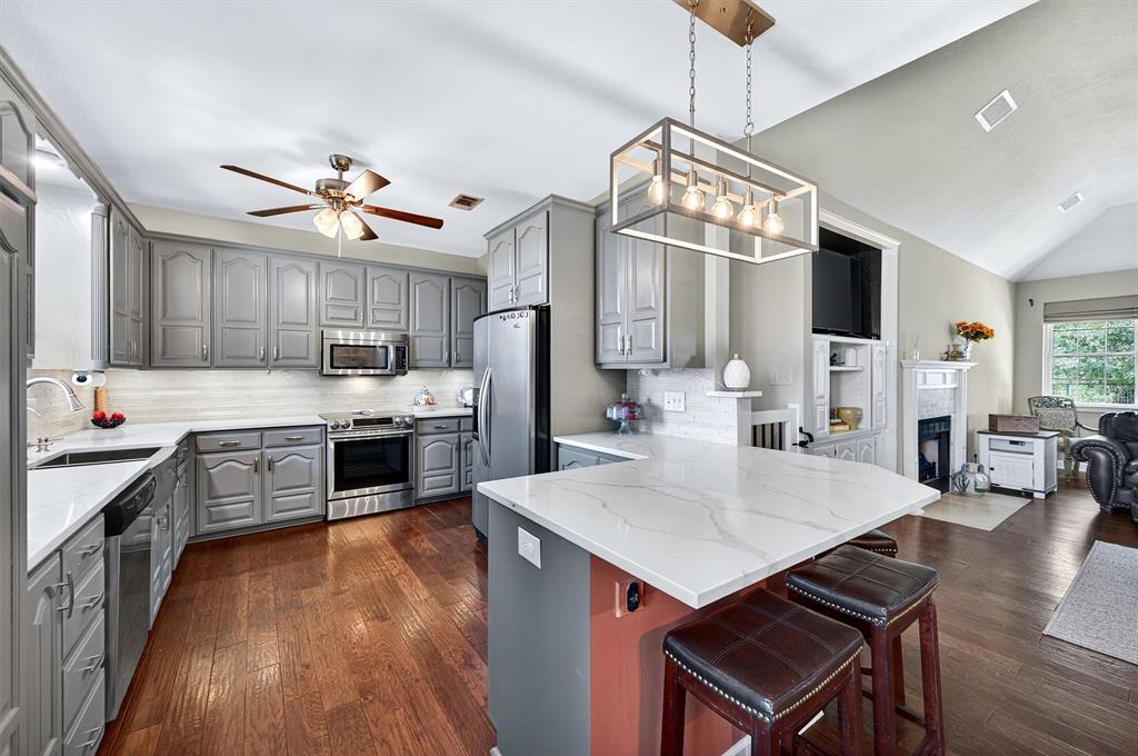 551 Massey Road Gunter, TX 75058 - Photo 8 of 40 a large kitchen with stainless steel appliances granite countertop a stove a refrigerator a oven a sink a dining table and chairs with wooden floor