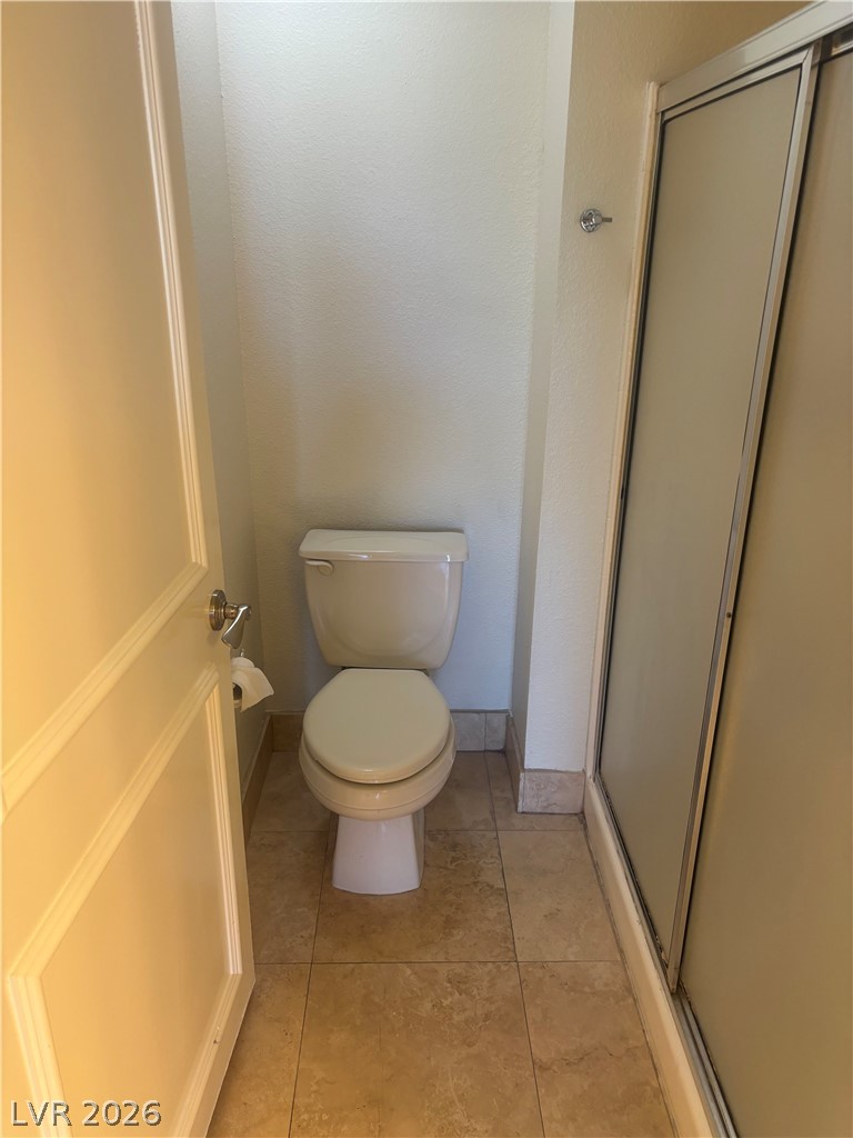 210 East Flamingo Road, Unit 123 Las Vegas, NV 89169 - Photo 11 of 17 A private water closet showcases neutral tile flooring and an adjacent walk-in shower enclosure.