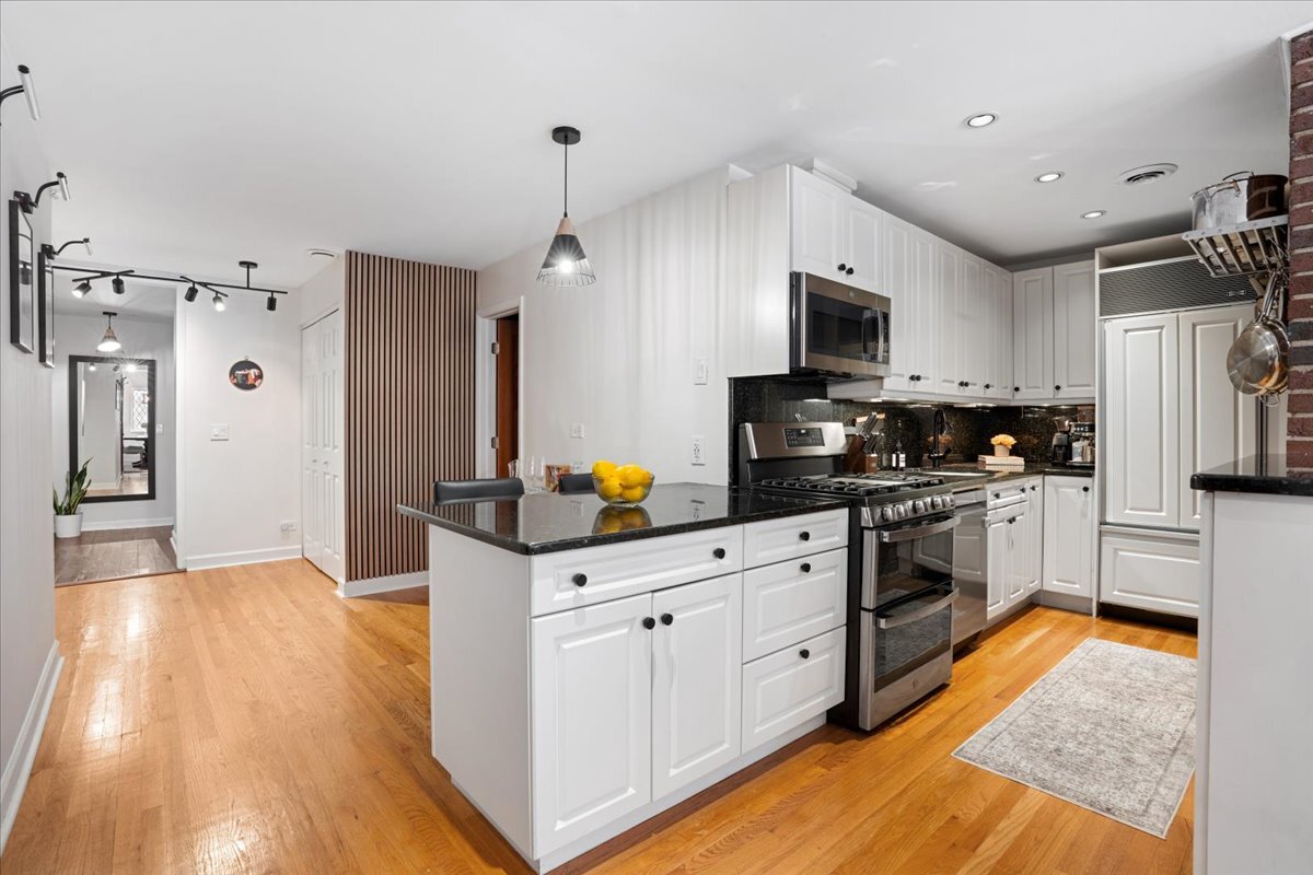 Undisclosed Address Chicago, IL 60613 - Photo 8 of 19 a kitchen with stainless steel appliances granite countertop a refrigerator a stove top oven a sink dishwasher and white cabinets with wooden floor