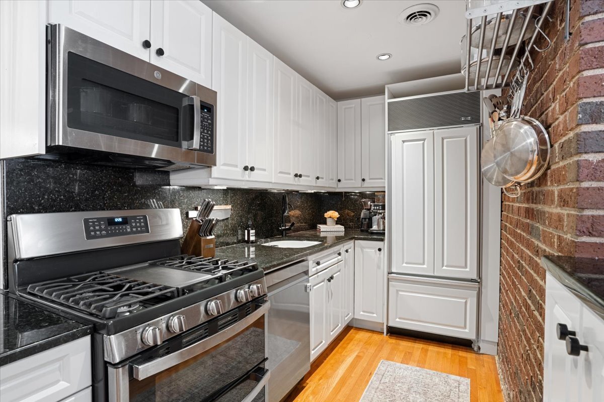 Undisclosed Address Chicago, IL 60613 - Photo 9 of 19 a kitchen with stainless steel appliances a stove a microwave and cabinets