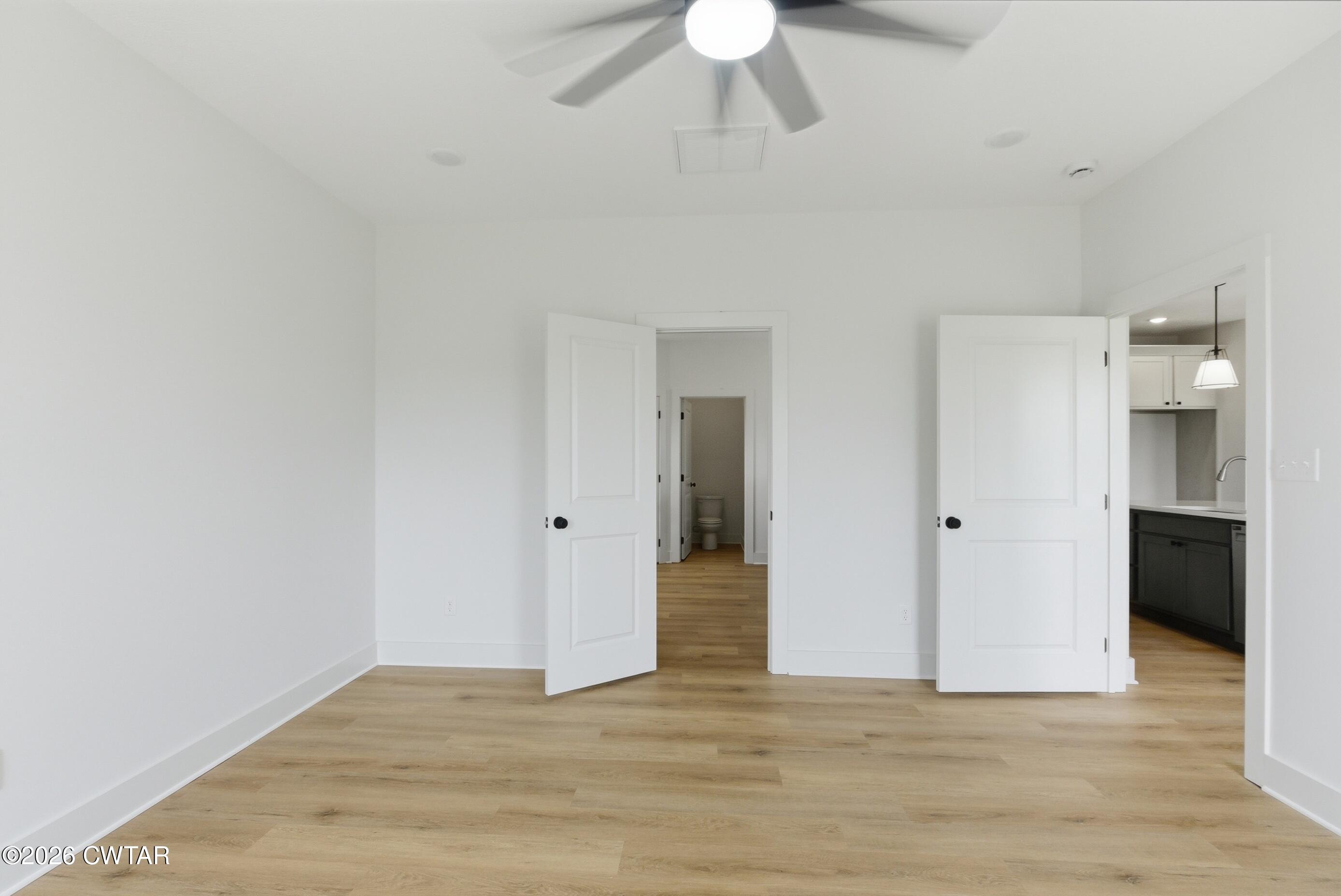 179 Daybreak Loop Medina, TN 38355 - Photo 22 of 32 a view of an empty room with wooden floor and a ceiling fan