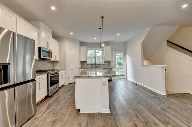 a kitchen with a center island wooden floor and stainless steel appliances