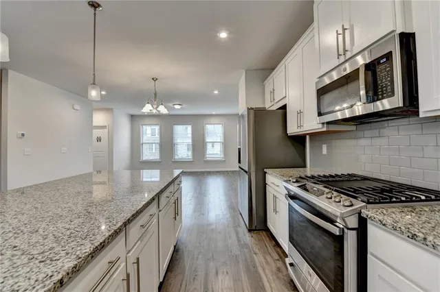 a kitchen with stainless steel appliances granite countertop a stove a microwave and wooden cabinets