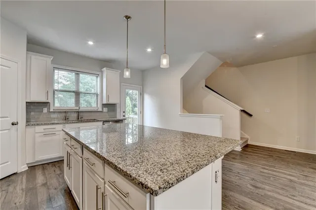 a kitchen with stainless steel appliances granite countertop a sink a oven a counter space and wooden floor