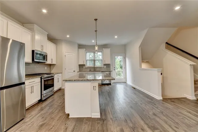 a kitchen with kitchen island granite countertop a sink cabinets and stainless steel appliances