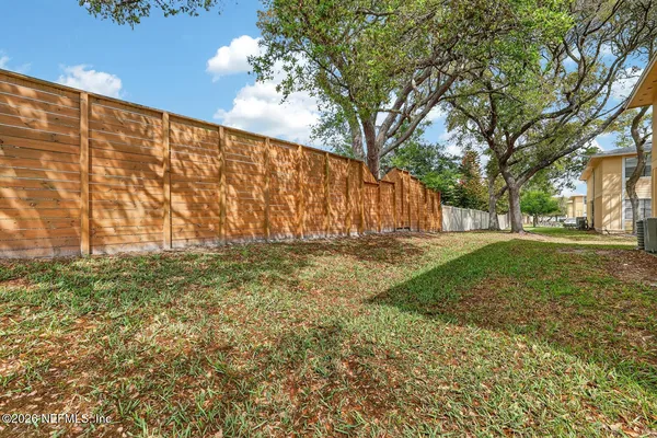 a backyard of a house with plants and large tree