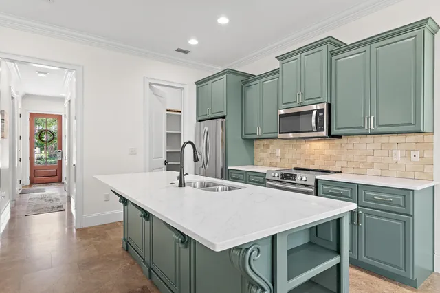 a kitchen with stainless steel appliances a sink a stove a refrigerator cabinets and a counter top space