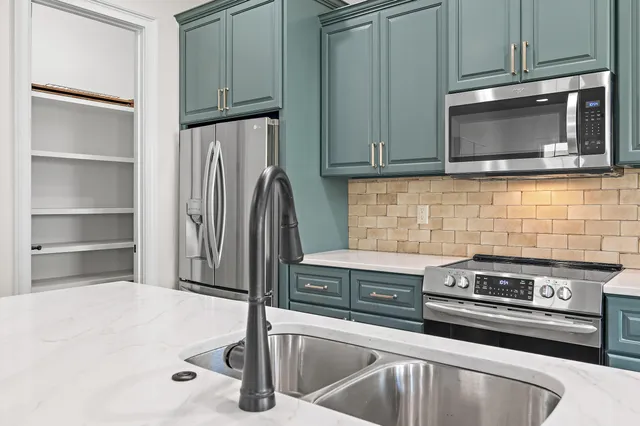 a kitchen with granite countertop a sink stainless steel appliances and cabinets