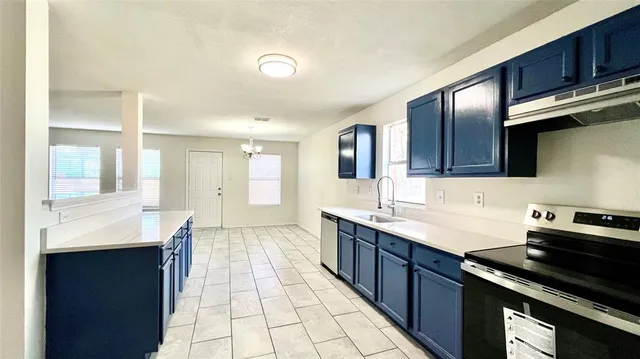 a large kitchen with stainless steel appliances a sink a counter space and cabinets