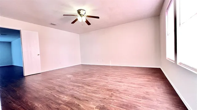 an empty room with wooden floor and windows