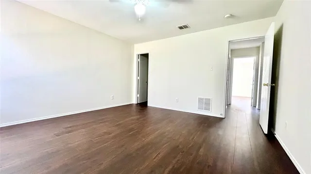 an empty room with wooden floor and fan
