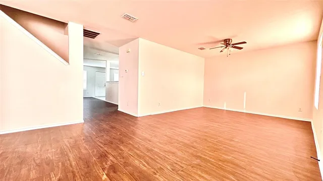 a view of a room with wooden floor and a ceiling fan