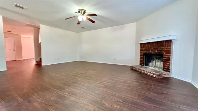 a view of an empty room with wooden floor fireplace and a window