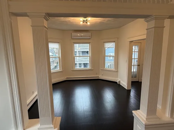 a view of an empty room with wooden floor and a window