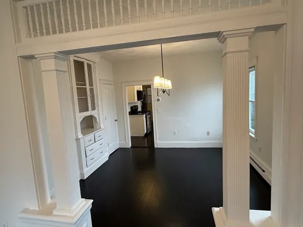 a view of a hallway with wooden floor and a bathroom