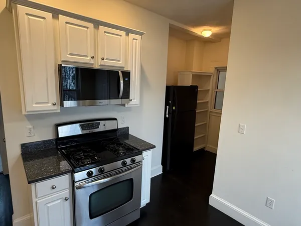 a kitchen with granite countertop white cabinets and stainless steel appliances