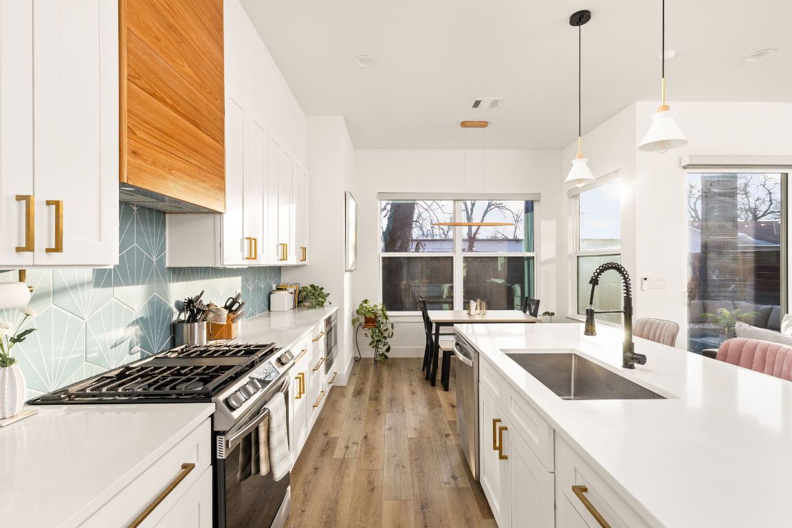 5109 Glissman Road, Unit 1 Austin, TX 78702 - Photo 8 of 39 Kitchen with white cabinetry, appliances with stainless steel finishes, pendant lighting, and light wood-type flooring
