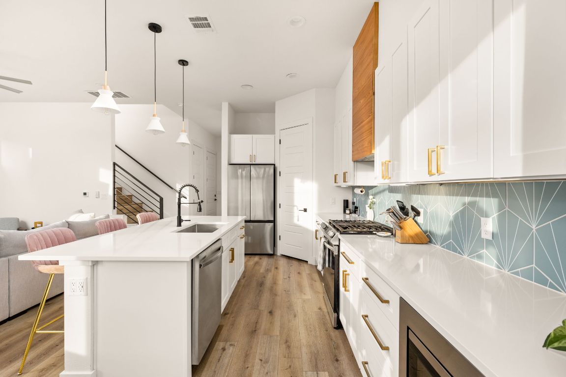 5109 Glissman Road, Unit 1 Austin, TX 78702 - Photo 9 of 39 Kitchen featuring stainless steel appliances, pendant lighting, a kitchen breakfast bar, a kitchen island with sink, and light wood finished floors