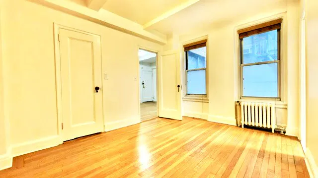 a view of a bedroom with wooden floor and a bathroom