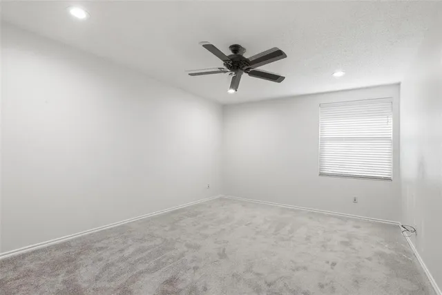 an empty room with a window and a fan
